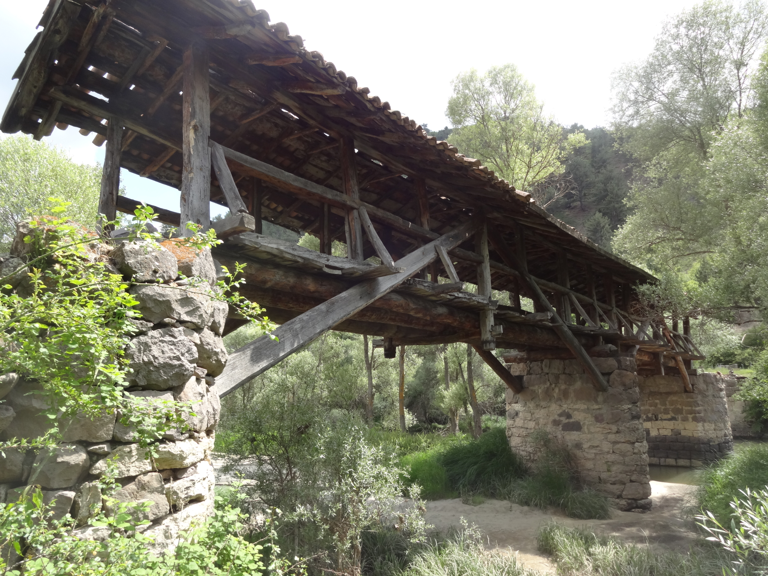 Resim 1. Tarihi Güvem Köprüsü: genel görünüşü (solda), beşik çatı ve ahşap dikmelerin köprü içinden görünüşü (sağda). Image 1. The Historic Güvem Bridge: general view (on the left), view from inside of the bridge showing the gable roof and wooden pillars (on the right).