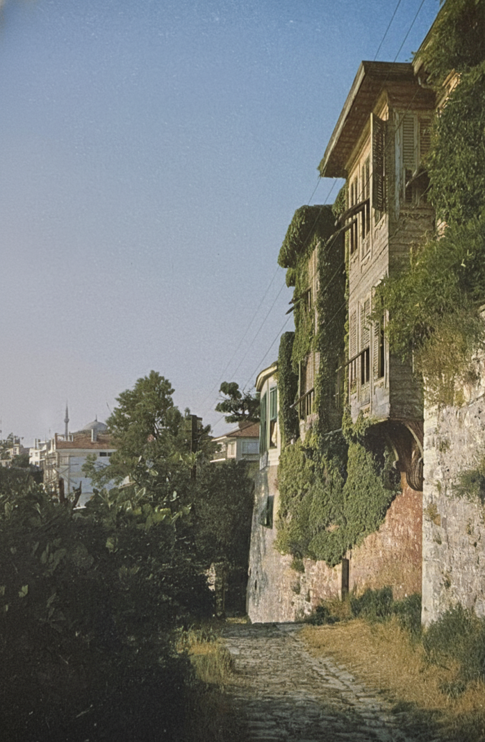 Resim 1. Çürüksulu Yalısı'nın restore edilmeden önceki haliyle birlikte, Üsküdar-Salacak'tan çevrenin geleneksel karakterini yansıtan bir görünüş (1962). Aradan geçen yaklaşık otuz yıllık sürede koruma konusunda yayımlanmış tüm yazılara, kitaplara, bilimsel çalışmalara, düzenlenmiş açık oturumlara, seminerlere, sempozyumlara, kokteyllere rağmen, ne yazık ki Üsküdar'da artık böylesine tipik bir sokağa rastlamak mümkün deği!!
